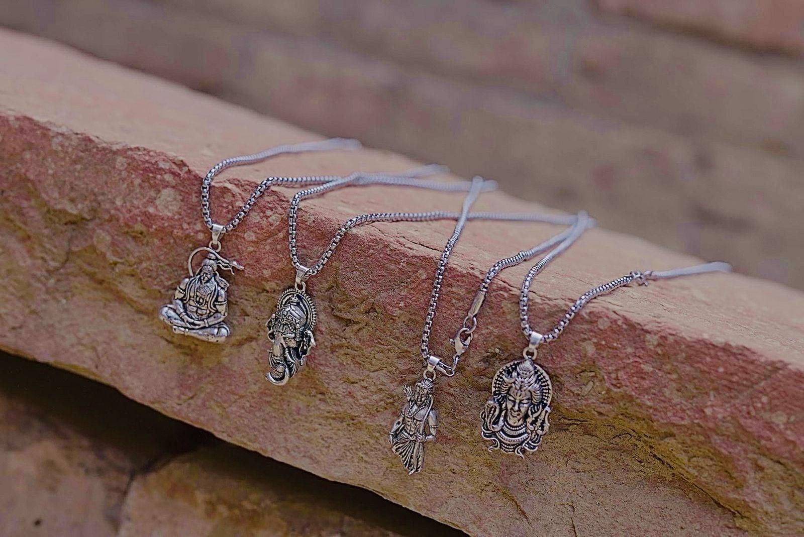 Silver necklaces with pendants on a stone surface